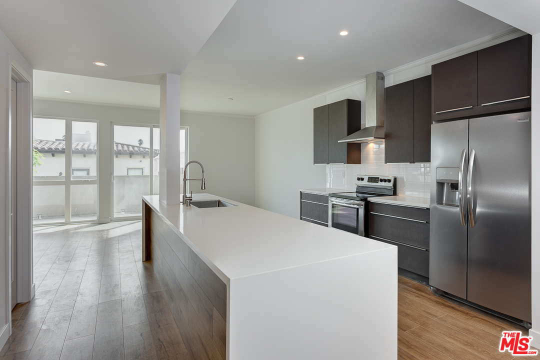 a kitchen with kitchen island a counter top a sink stainless steel appliances and cabinets