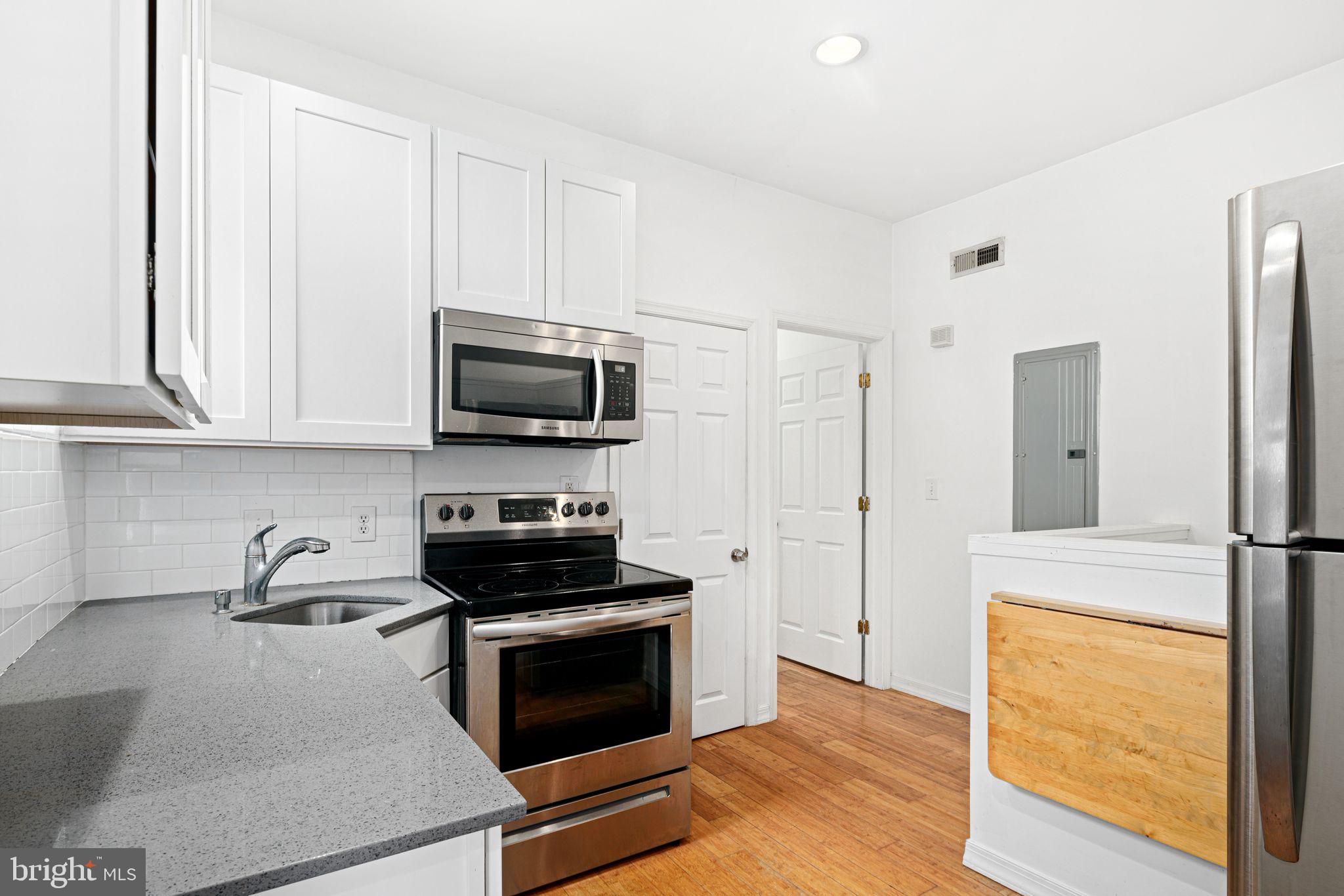 a kitchen with stainless steel appliances granite countertop white cabinets and a stove