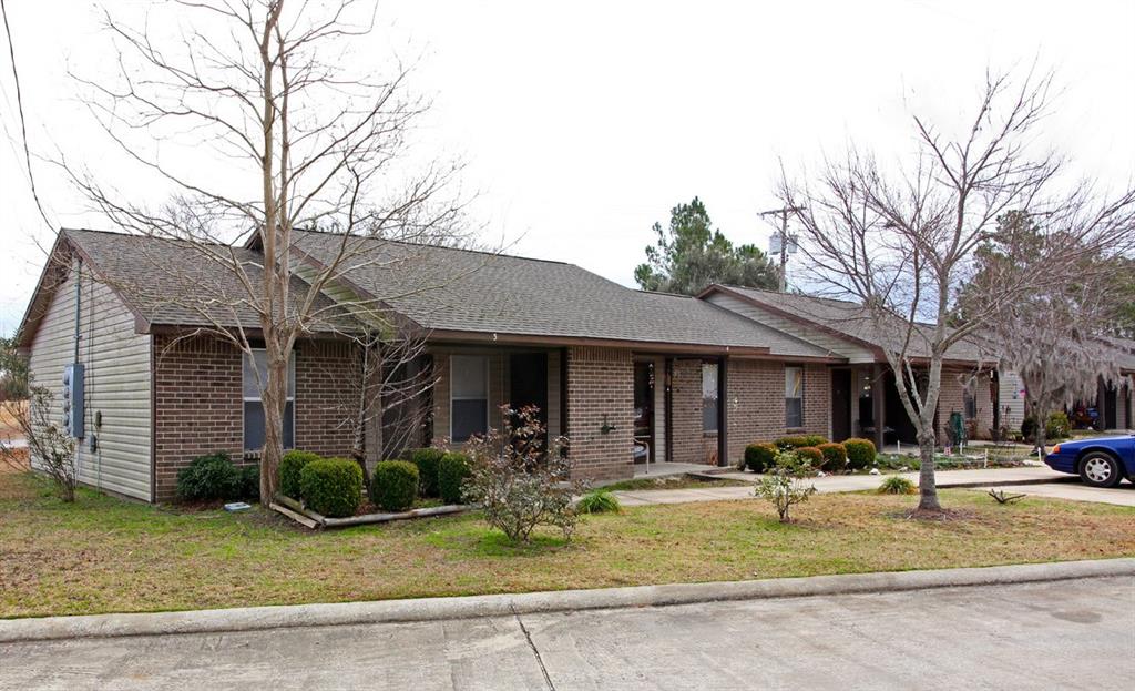 a front view of a building with garden and trees