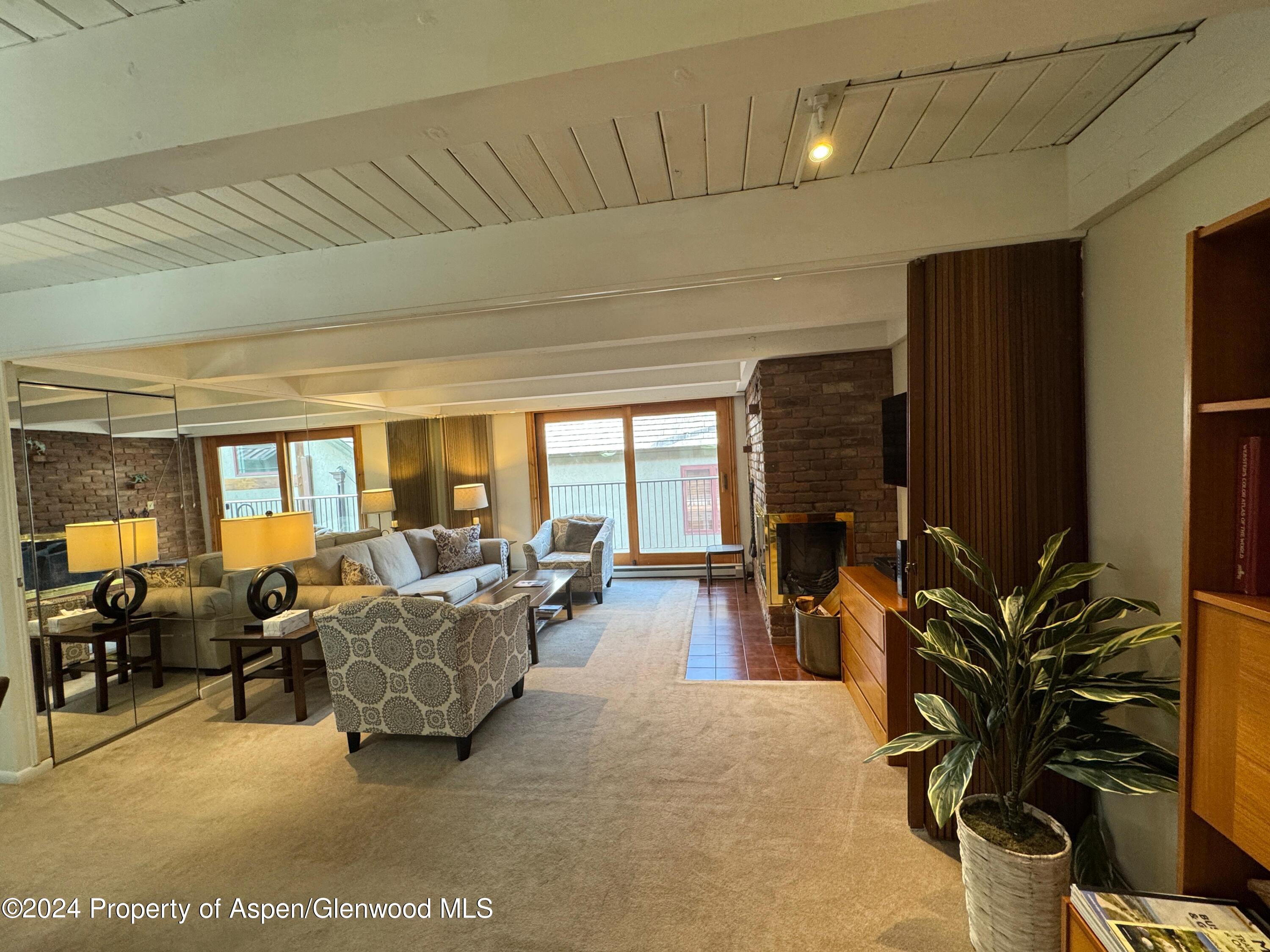 a living room with furniture large windows and flat screen tv