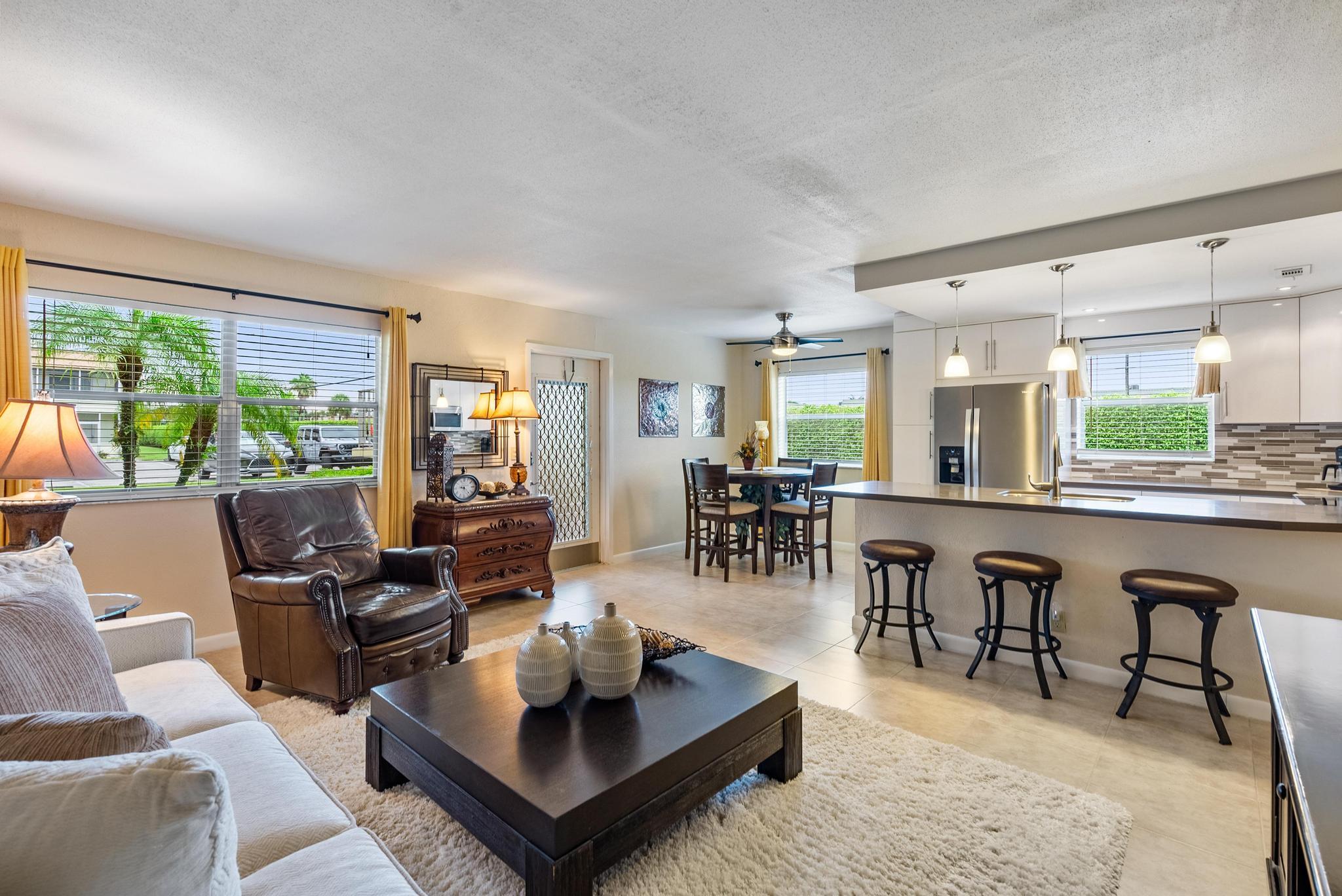 a living room with furniture a large window and dining table