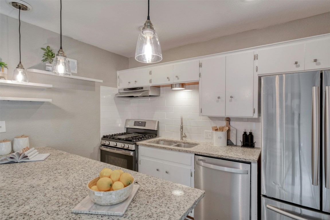 a kitchen with stainless steel appliances granite countertop a sink a stove and a refrigerator