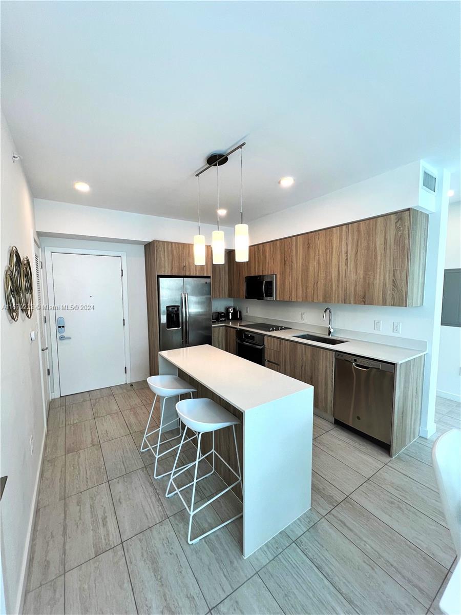 a kitchen with stainless steel appliances kitchen island granite countertop a table chairs sink and cabinets