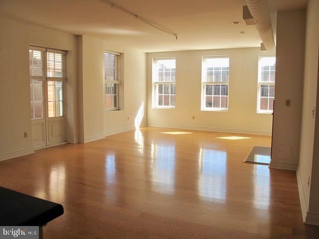 a view of empty room with wooden floor and fan