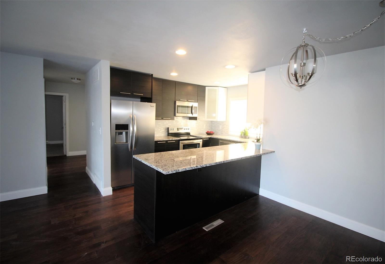 a kitchen with kitchen island granite countertop a sink and a refrigerator