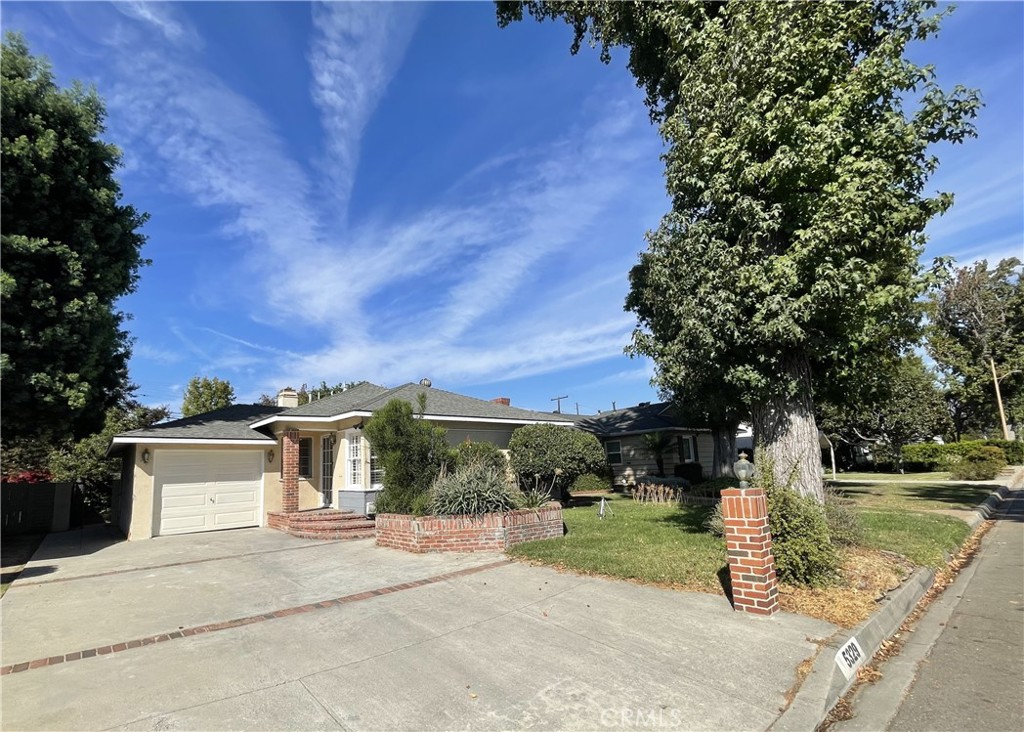 a front view of a house with a yard and tree