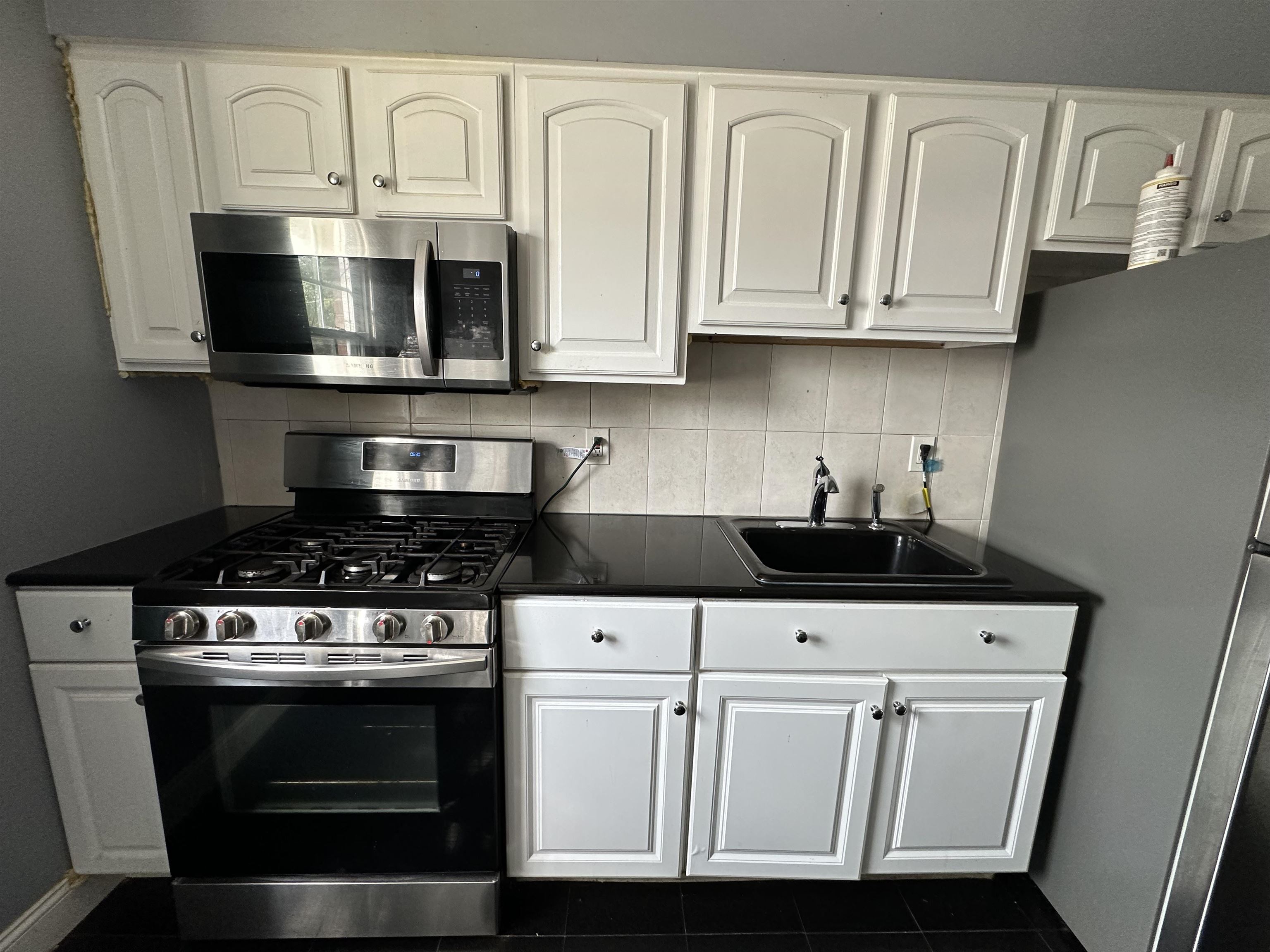 a kitchen with stainless steel appliances granite countertop white cabinets and a stove a oven with white countertops