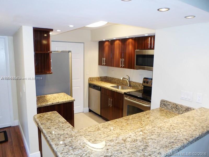 a kitchen with stainless steel appliances kitchen island granite countertop a refrigerator and a stove top oven