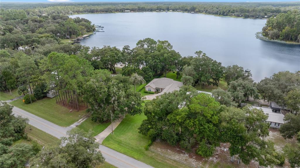 an aerial view of a house with a yard and lake view