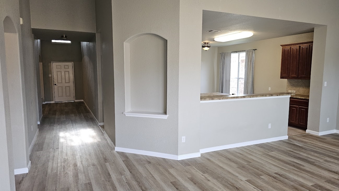 wooden floor in an empty room with a kitchen