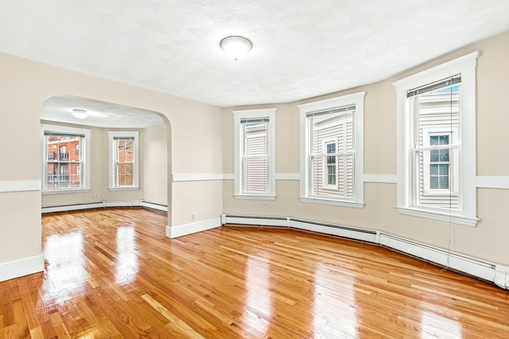 a view of an empty room with window and wooden floor