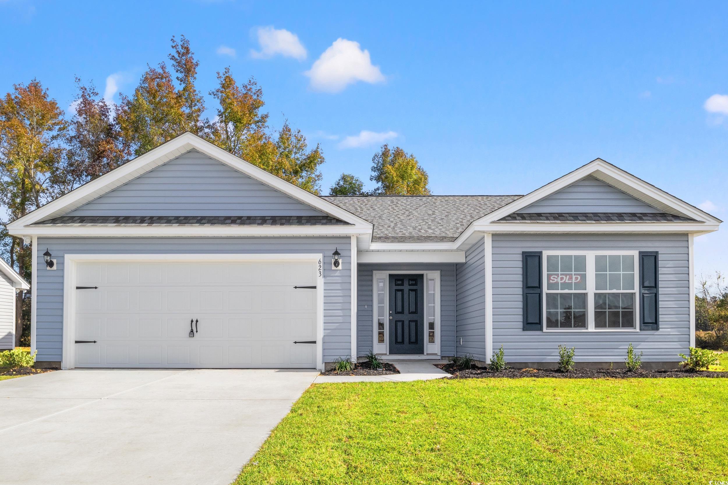 Single story home featuring a front yard and a gar