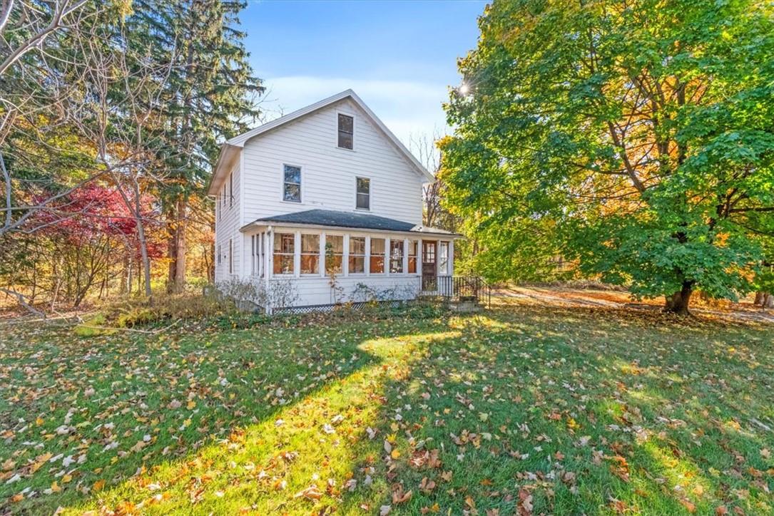 Rear view of house featuring a yard and a sunroom