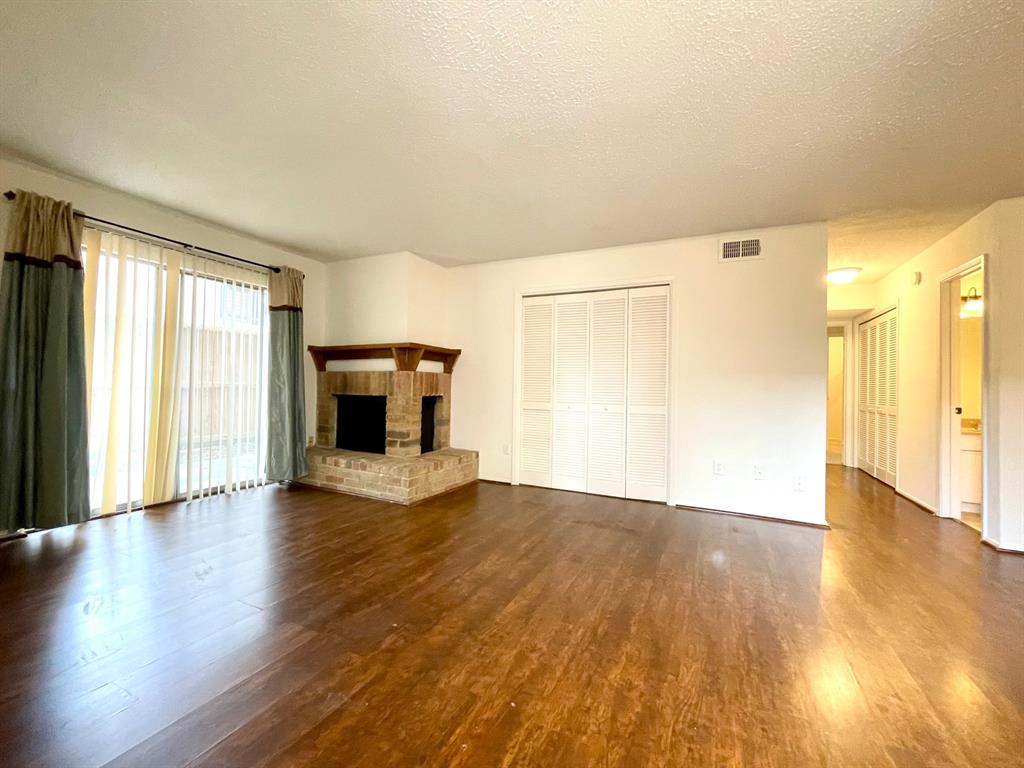 an empty room with wooden floor fireplace and windows