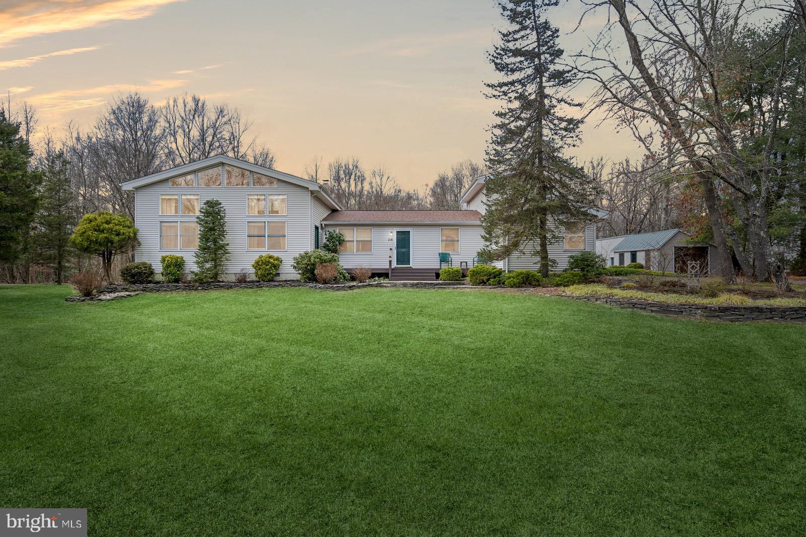 a front view of a house with a garden and trees