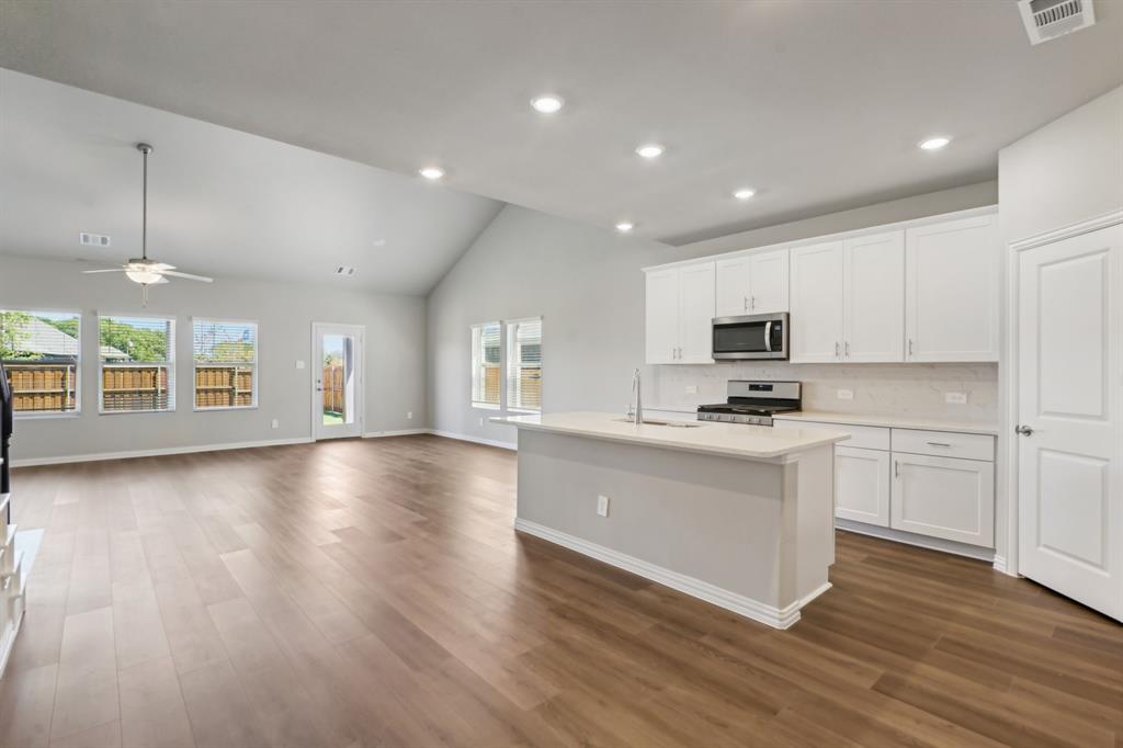 a view of kitchen with microwave a stove and wooden floor