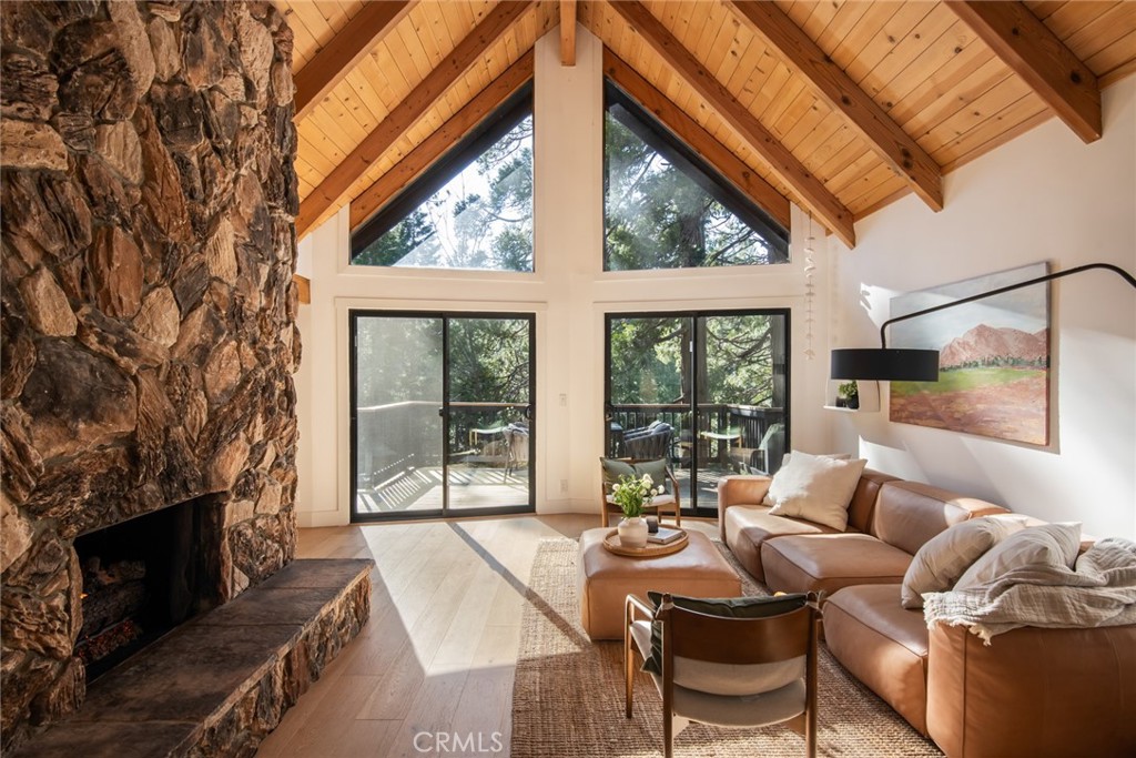 a living room with furniture a fireplace and floor to ceiling windows