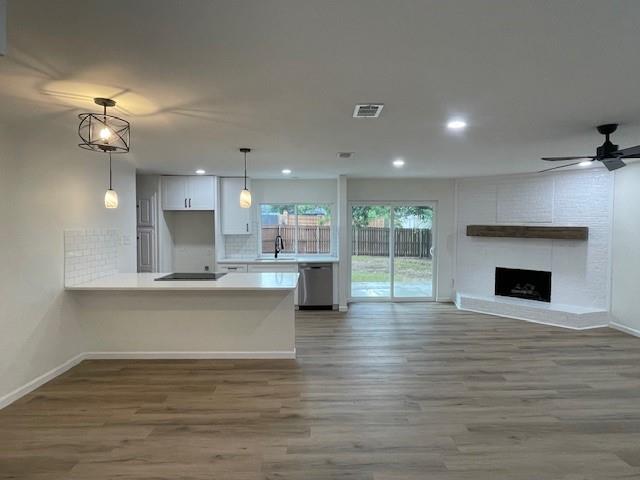 a view of an empty room and kitchen with wooden floor