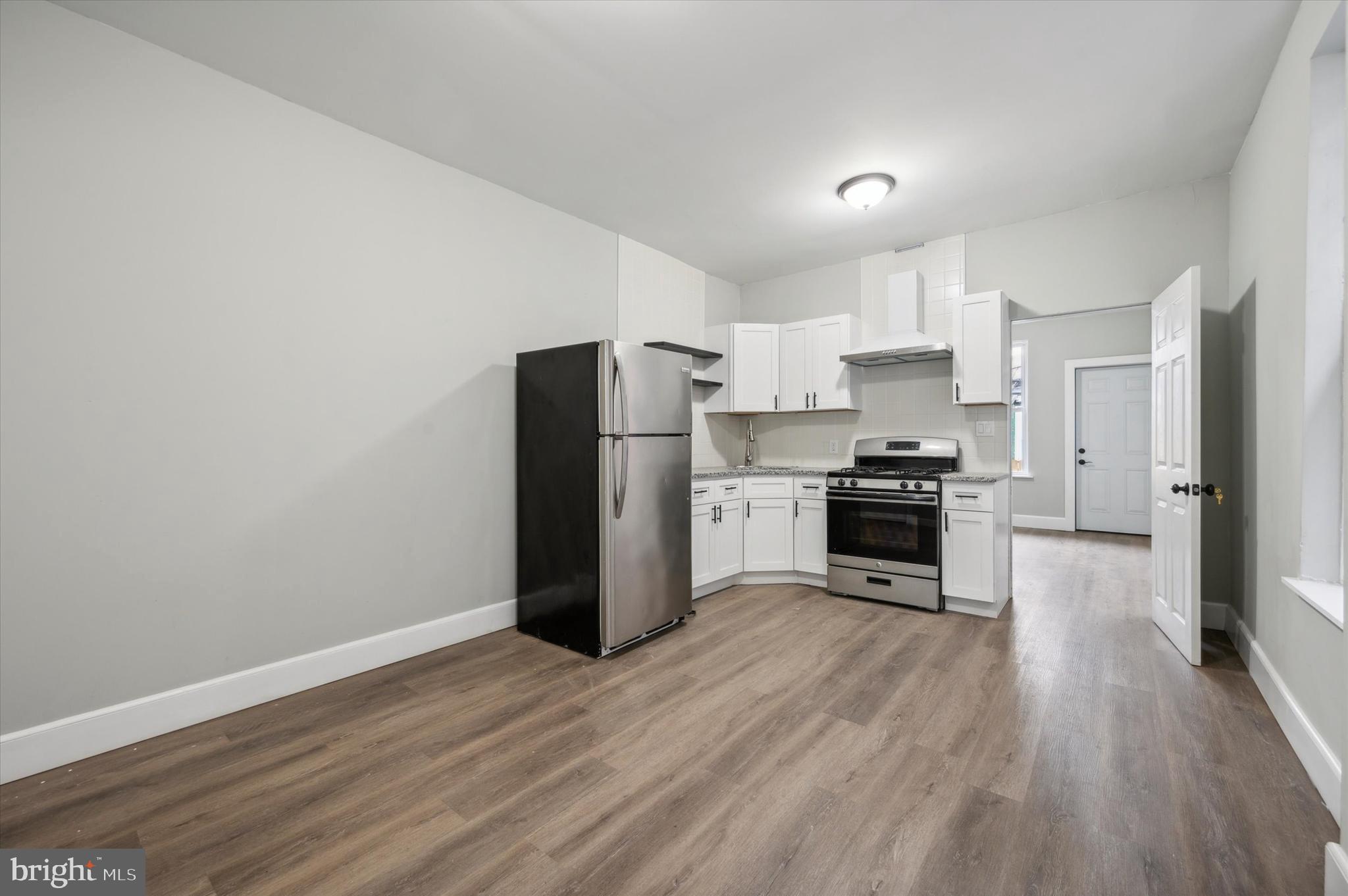 a kitchen with a refrigerator a stove top oven and wooden floor