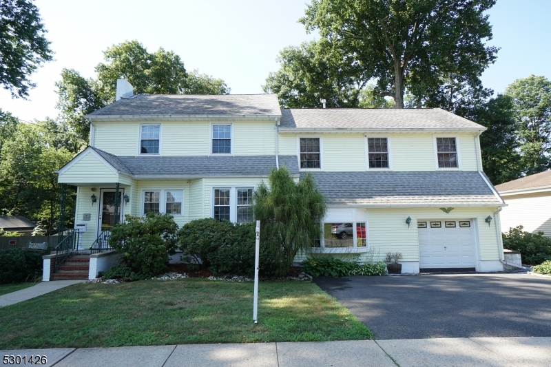 a front view of a house with a yard and trees