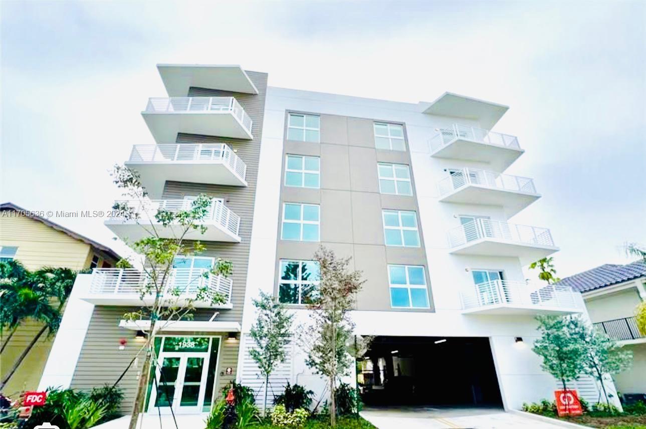 a front view of a multi story residential apartment building with yard