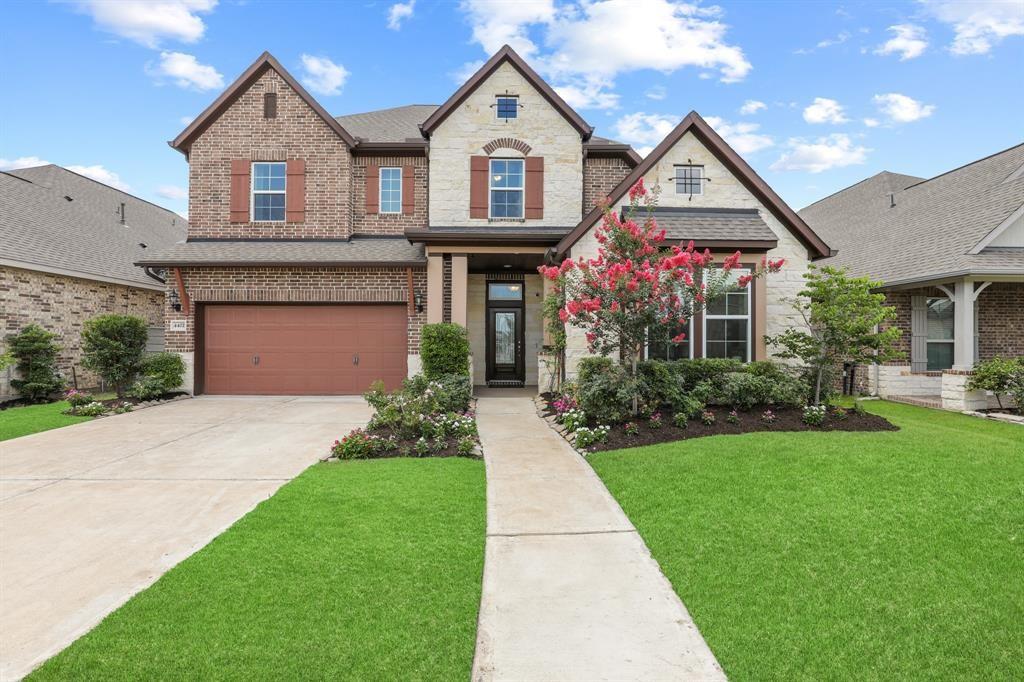 This is a two-story brick home with an attached two-car garage, welcoming entrance with a prominent gable and large windows.