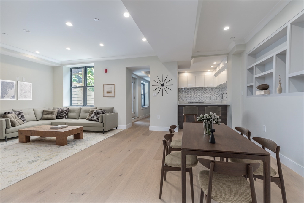 a living room with furniture kitchen view and a wooden floor