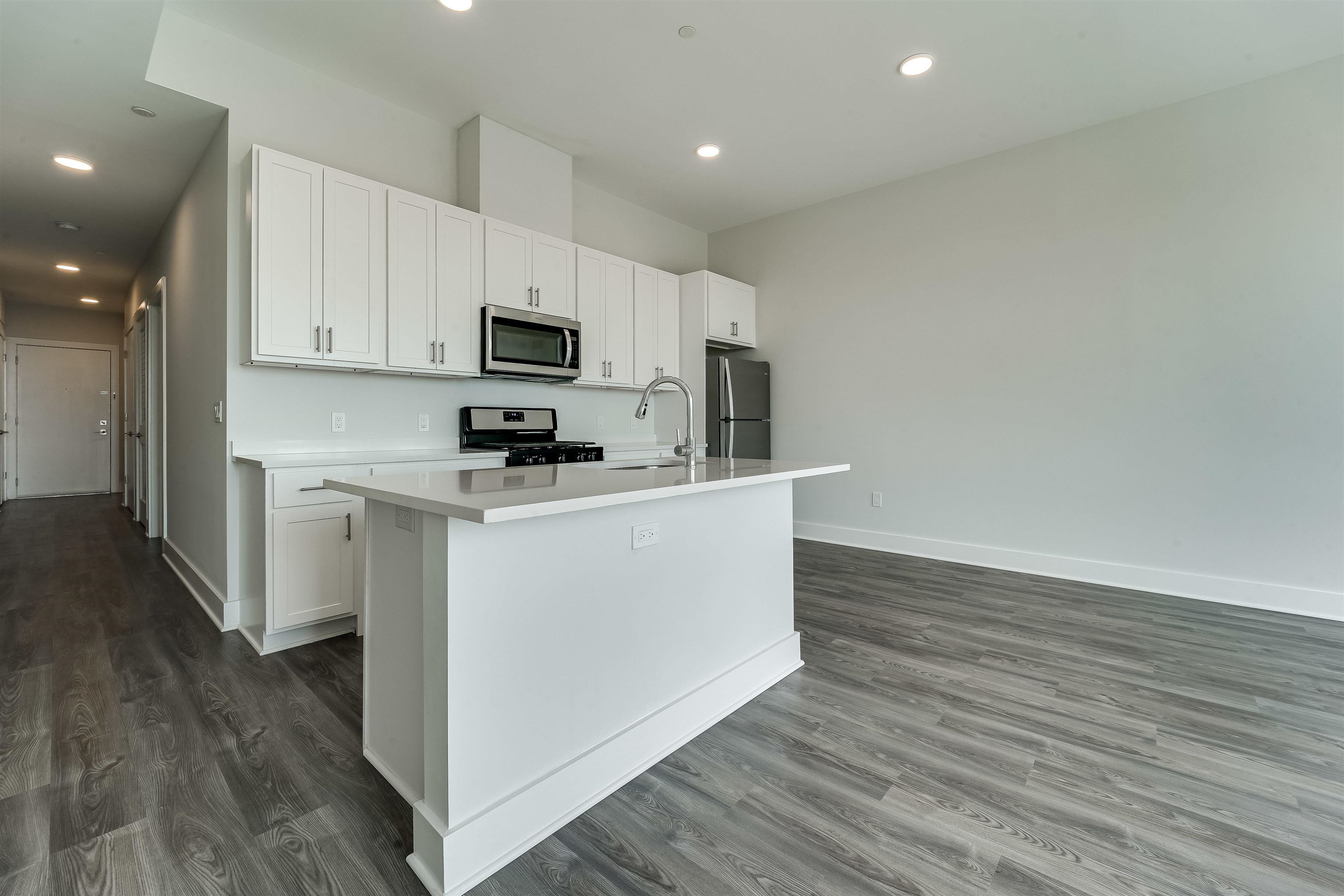 a kitchen with wooden floor white cabinets and stainless steel appliances