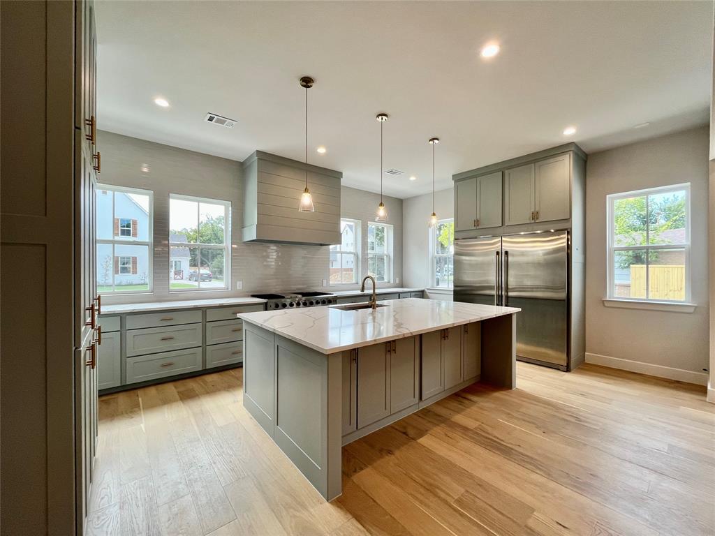 a large kitchen with cabinets wooden floor and stainless steel appliances