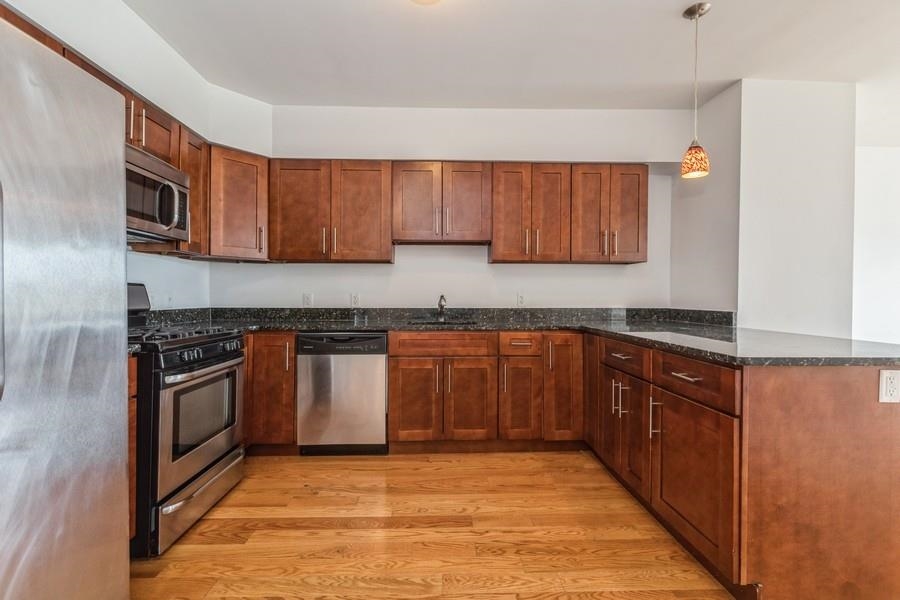 a kitchen with stainless steel appliances granite countertop a stove a sink and a microwave