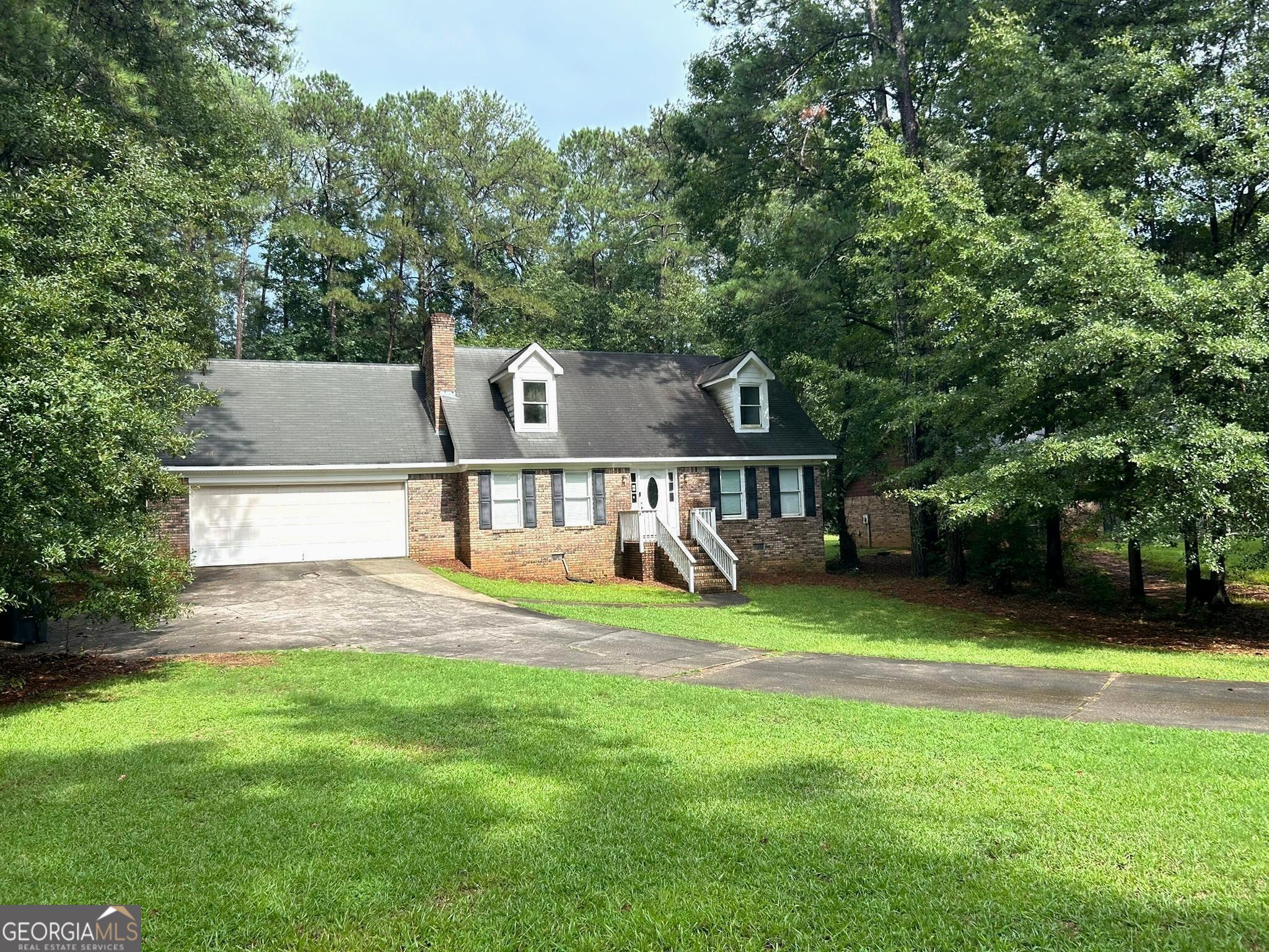 a view of a house with a big yard and large trees