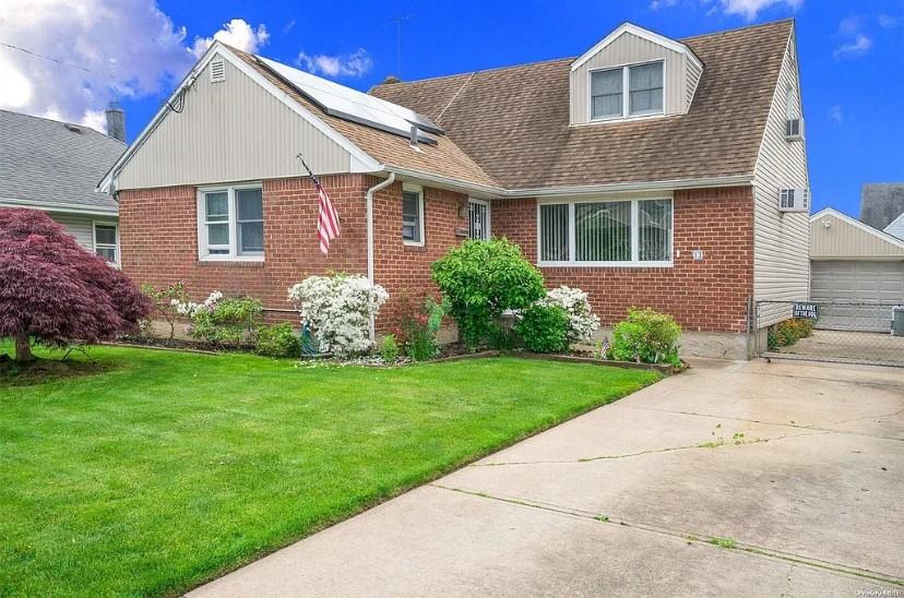 View of front facade with a front yard, solar panels, and a garage