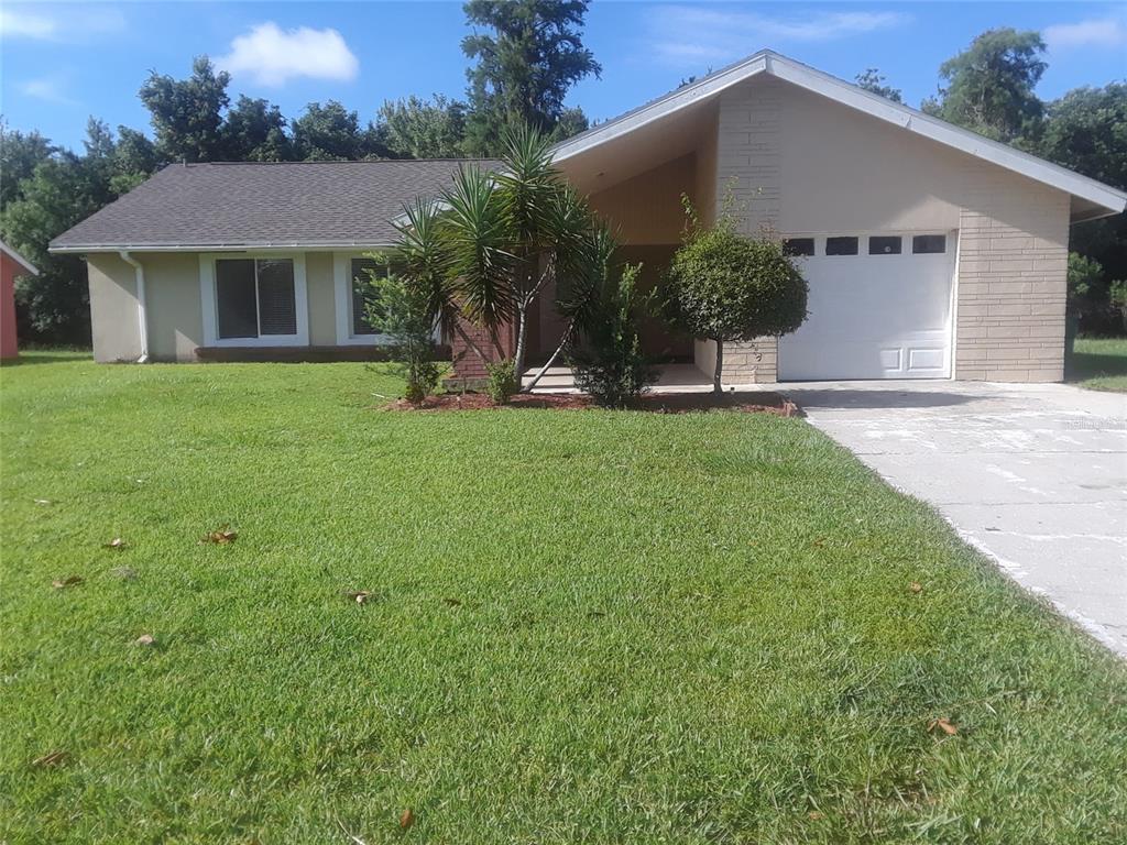 a front view of a house with a yard and potted plants