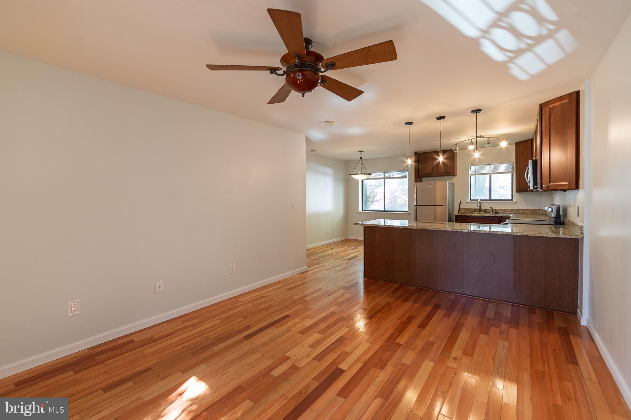 a kitchen with stainless steel appliances kitchen island wooden floors granite counter tops and a view of living room