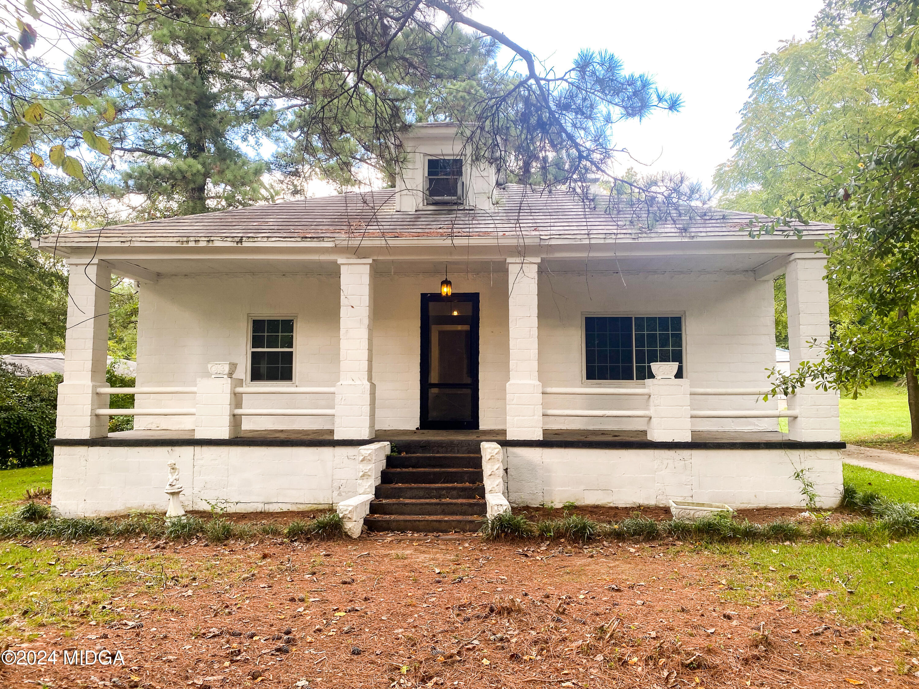 a view of a white house with large windows and a small yard