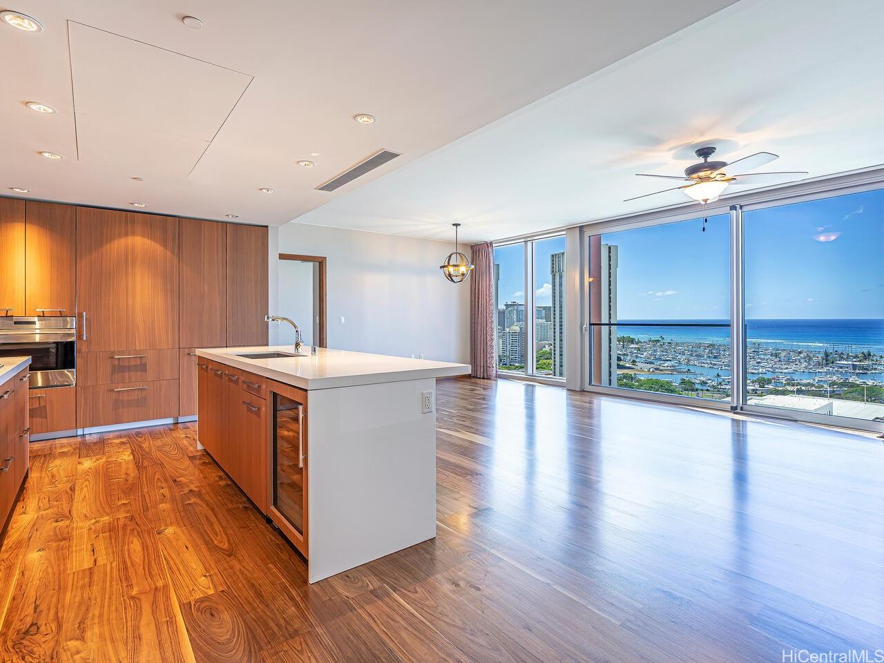 a view of a kitchen with kitchen island a sink wooden floor and a large window