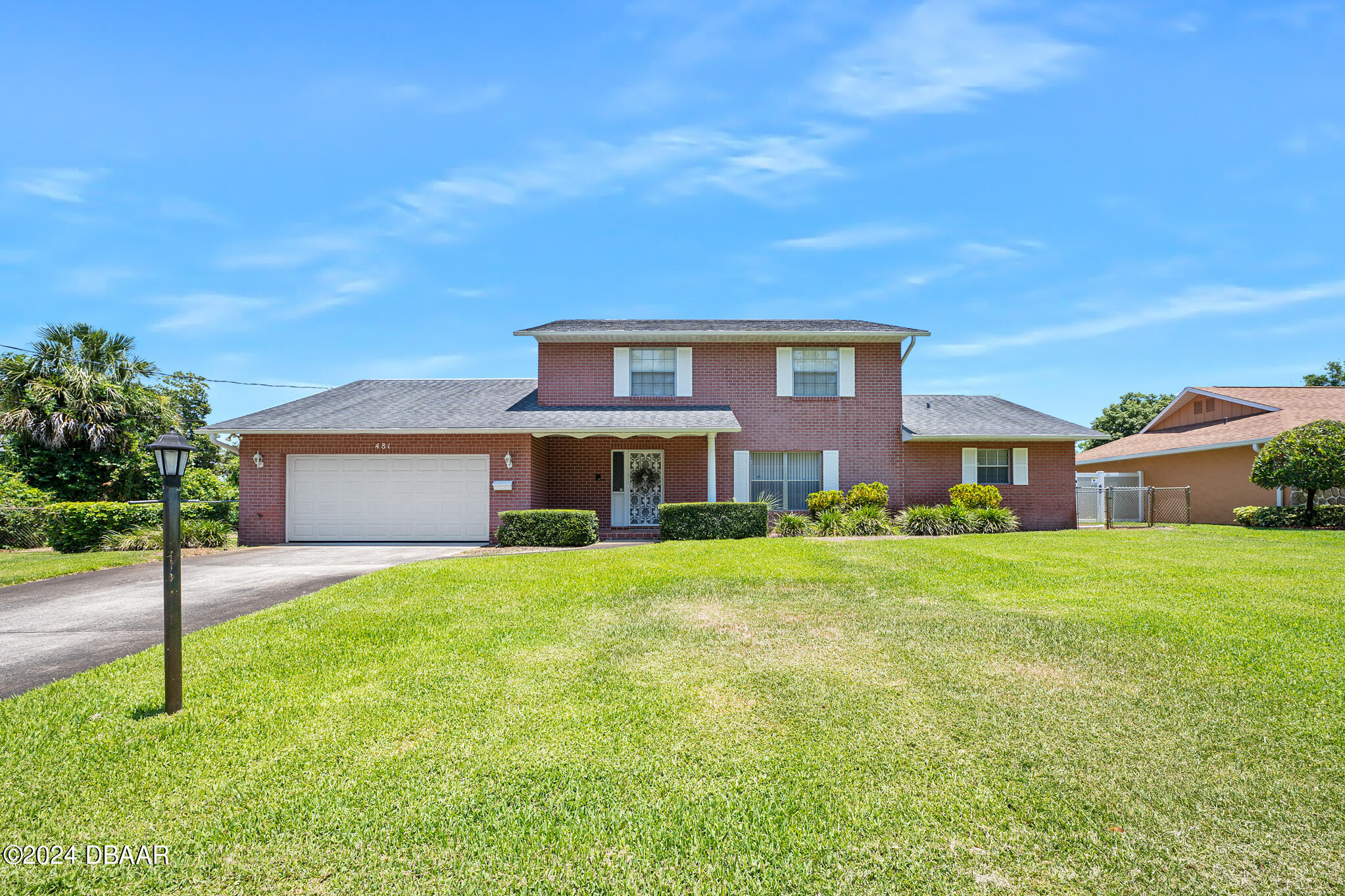 a brick house with a big yard and large trees