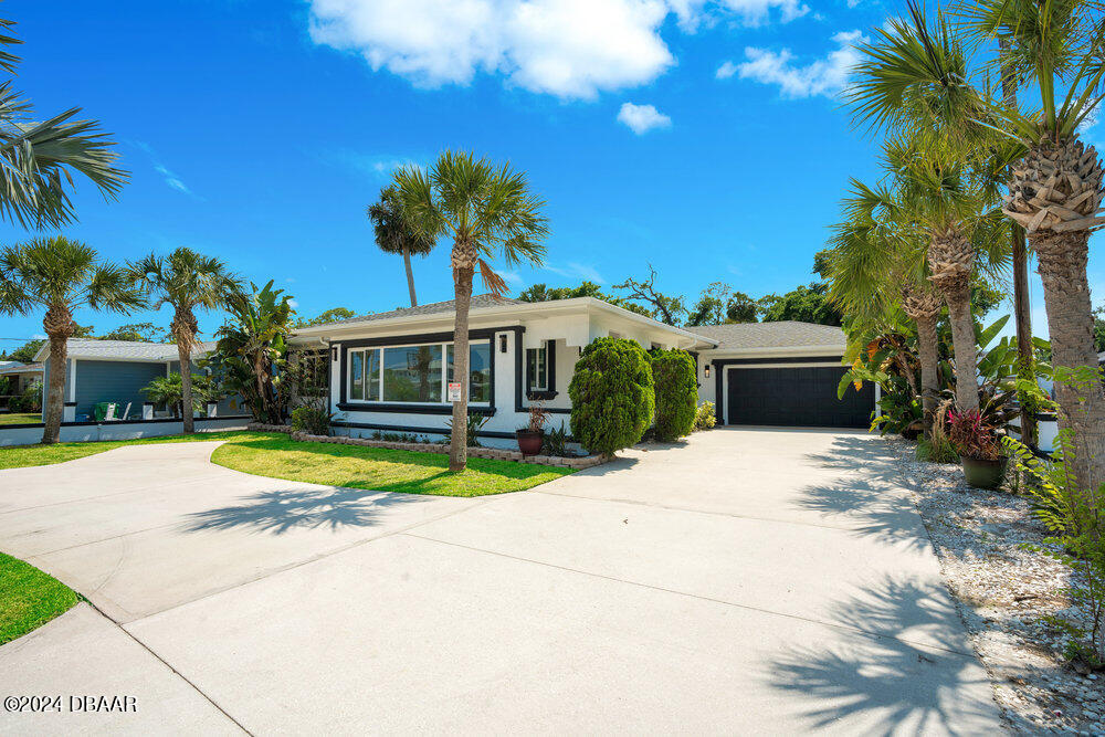 a front view of a house with a yard and palm trees