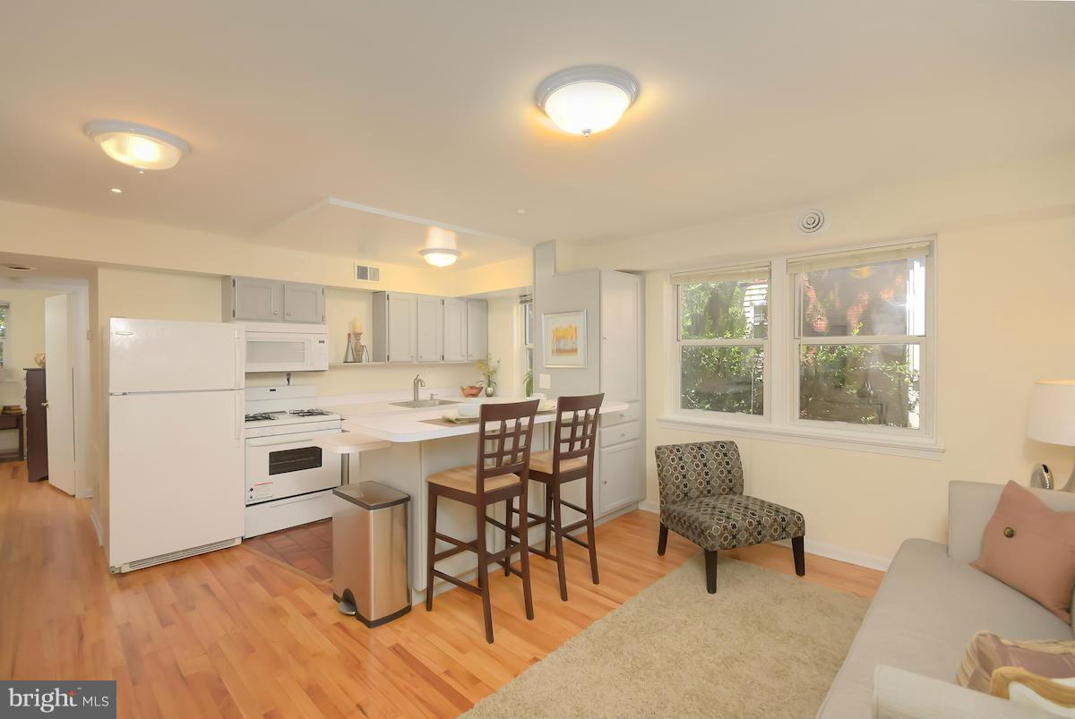 a living room with stainless steel appliances kitchen island granite countertop furniture and a wooden floor