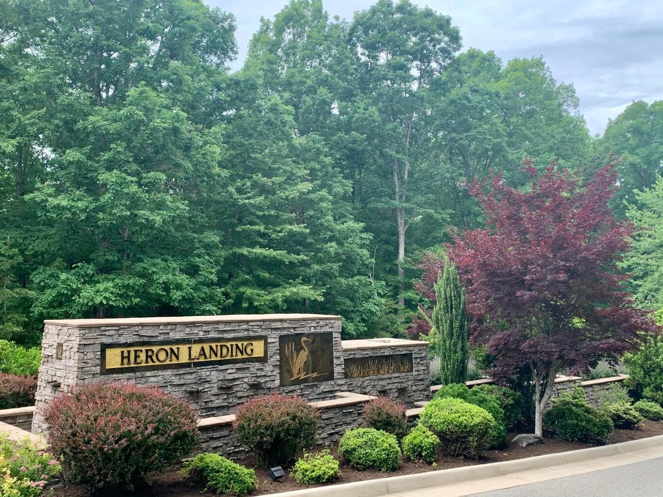 a view of sign board with yard and large trees