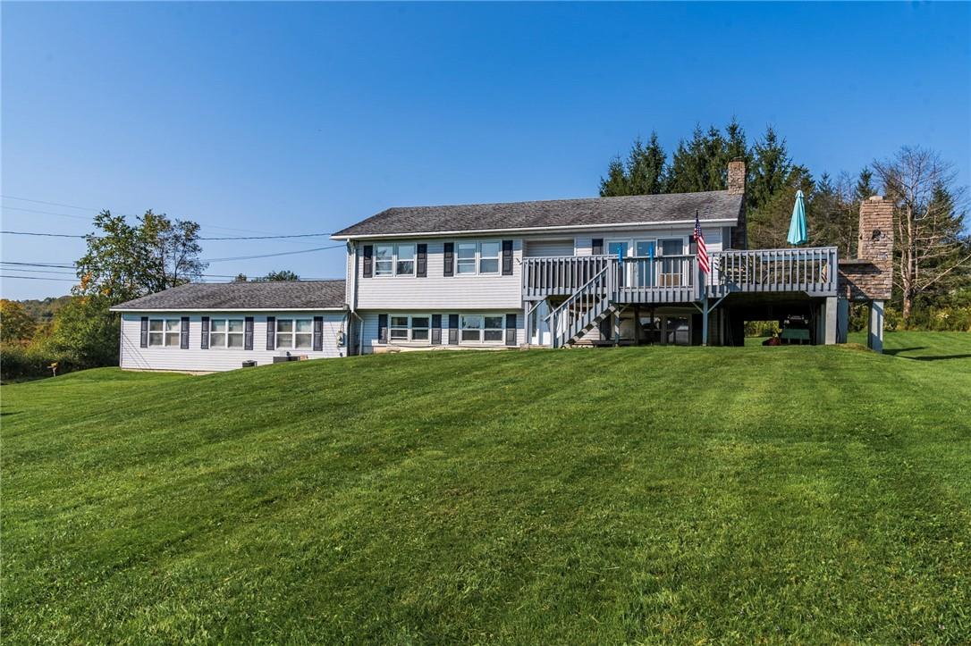 Rear view of house featuring a wooden deck and a yard