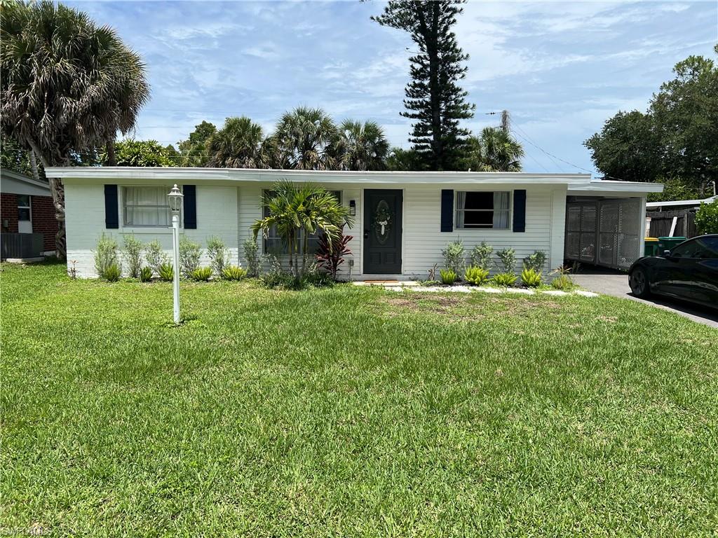 a front view of house with yard and trees in the background