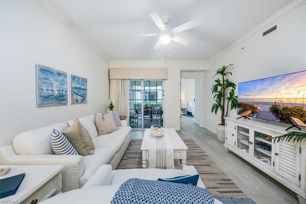 Living room with ceiling fan, light wood-type flooring, and crown molding