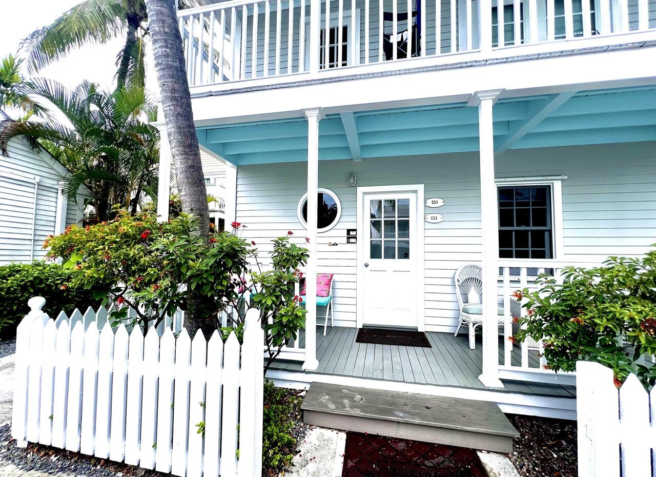 a view of a white house with a small window and potted plants