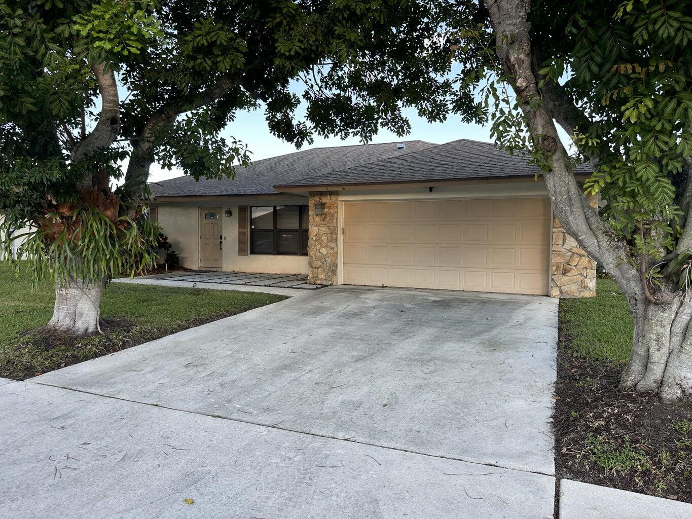 a front view of a house with yard and tree